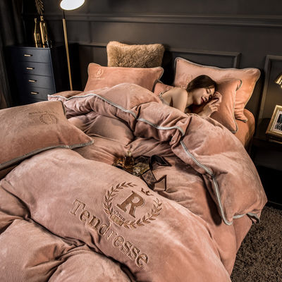 Un ensemble de lit en quatre pièces avec des broderies et des liens en peluche de lait