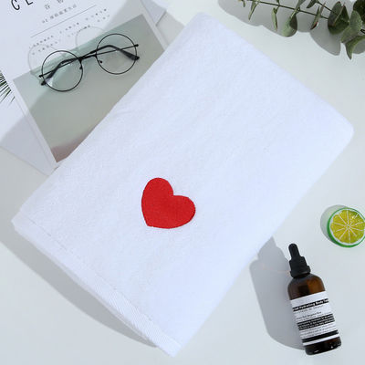 Une serviette de bain blanche douce et épaisse en coton pur avec une broderie personnalisée